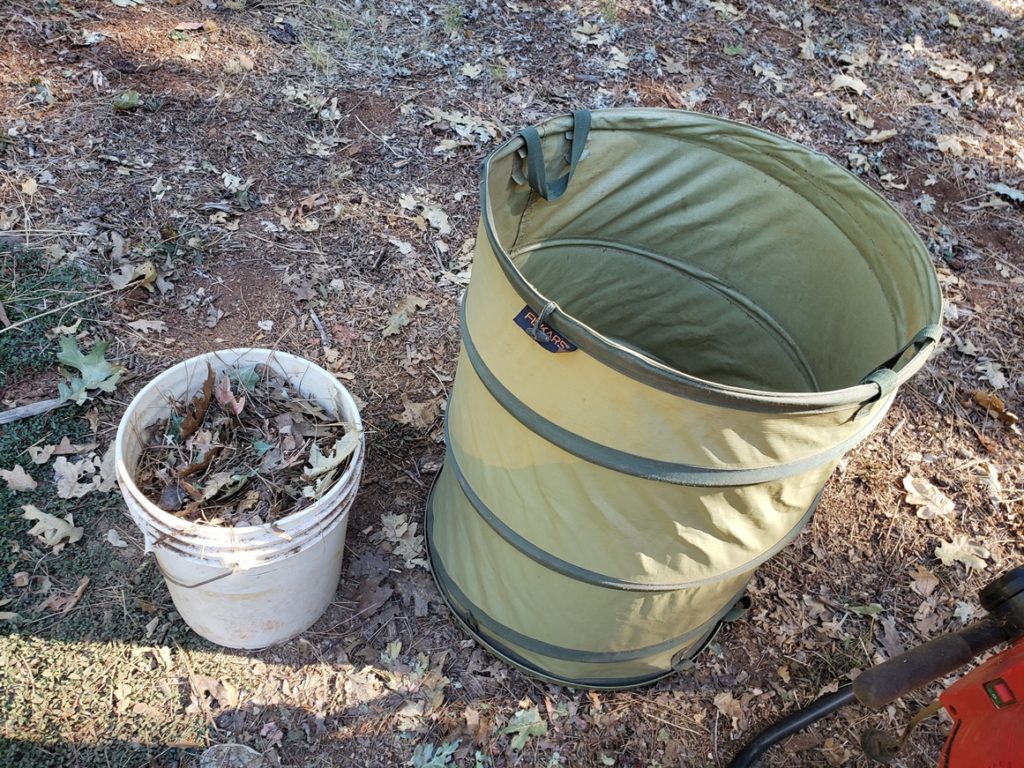 Shredded leaves from large bin to a small bucket